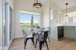 Light wood-finish flooring, white subway tile backsplash, white countertops, dual-tone cabinetry, and a large window - 
