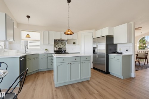 Kitchen featuring two-tone cabinetry, white countertops, subway tile backsplash, and wood-finish flooring - 839 Blacklock Way Sw, Edmonton, AB 