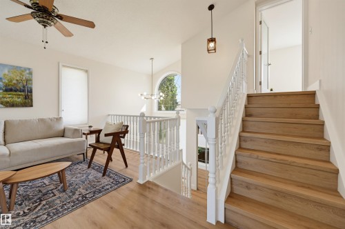 Wood-finish flooring, white spindle staircase, arched window, ceiling fan, and pendant lighting - 839 Blacklock Way Sw, Edmonton, AB 
