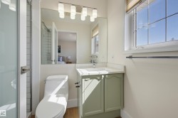 Enclosed glass shower stall, single vanity with light green cabinetry, white countertop, and a window with natural light - 