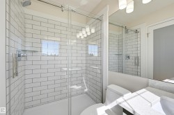 Shower with subway tile surround, glass enclosure, and rainfall shower head - 