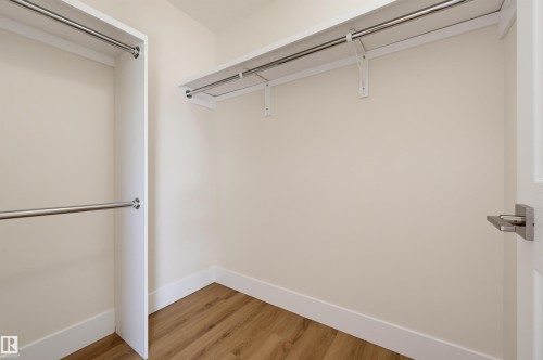 Walk-in closet with wood-finish flooring, white walls, and built-in shelving with hanging rods - 839 Blacklock Way Sw, Edmonton, AB 