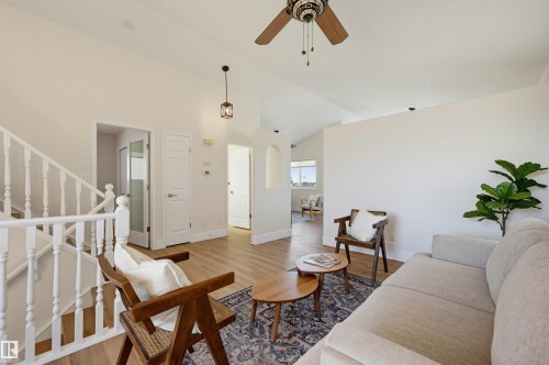 Vaulted ceilings with a ceiling fan, light wood-finish flooring, white staircase with balusters, recessed lighting, and a decorative pendant light fixture - 839 Blacklock Way Sw, Edmonton, AB 