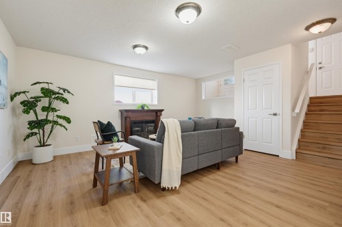 Light wood-finish flooring, a fireplace with a wood mantel, white paneled doors, and a wood staircase - 839 Blacklock Way Sw, Edmonton, AB 