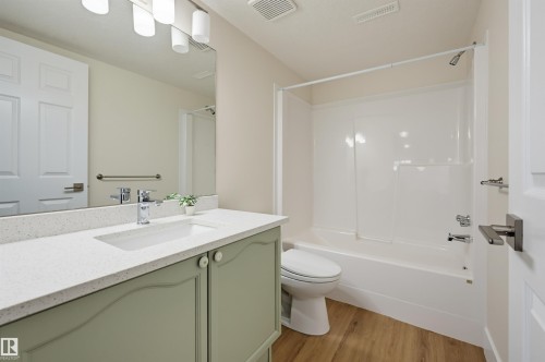 Contemporary bathroom featuring a light green vanity with white knobs, a white integrated sink, and a chrome faucet - 839 Blacklock Way Sw, Edmonton, AB 