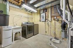 Laundry area featuring a utility sink, a clothes drying rack, and exposed overhead utilities - 