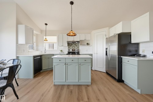 Kitchen featuring a central island, wood-finish flooring, white subway tile backsplash, and light-toned cabinetry - 839 Blacklock Way Sw, Edmonton, AB 
