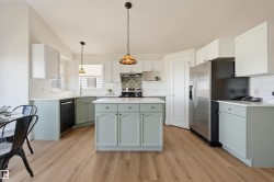 Kitchen featuring a central island, wood-finish flooring, white subway tile backsplash, and light-toned cabinetry - 