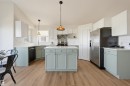 Kitchen featuring a central island, wood-finish flooring, white subway tile backsplash, and light-toned cabinetry - 839 Blacklock Way Sw, Edmonton, AB 