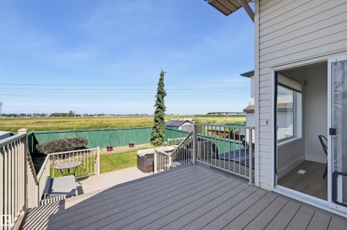 Spacious composite deck with white railings, offering direct access to a lower patio area and green space - 839 Blacklock Way Sw, Edmonton, AB 