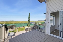 Spacious composite deck with white railings, offering direct access to a lower patio area and green space - 