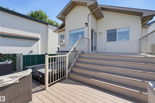 Multi-level composite deck with white railings, featuring a built-in hot tub, and direct access to the interior via a glass-paneled door - 839 Blacklock Way Sw, Edmonton, AB 