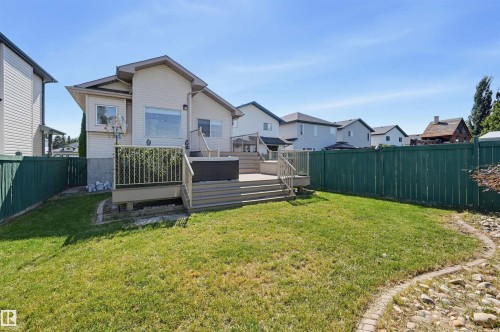 Expansive backyard featuring a manicured lawn, a multi-level deck with glass panel railing, and privacy fencing - 839 Blacklock Way Sw, Edmonton, AB 