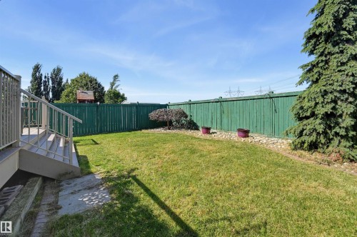 Expansive backyard featuring a manicured lawn, a painted wood fence, and a multi-level deck with handrails - 839 Blacklock Way Sw, Edmonton, AB 