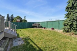 Expansive backyard featuring a manicured lawn, a painted wood fence, and a multi-level deck with handrails - 
