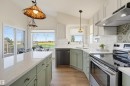 Kitchen featuring light-toned cabinetry, light-toned countertops, and wood-finish flooring - 839 Blacklock Way Sw, Edmonton, AB 