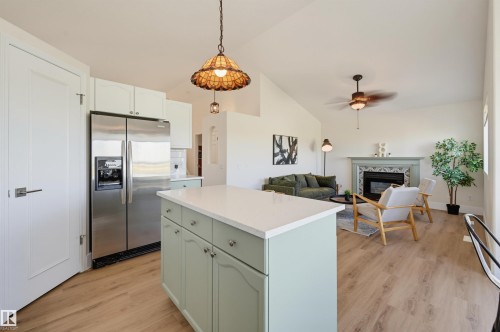 Open-concept living area with vaulted ceilings, wood-finish flooring, and a central kitchen island - 839 Blacklock Way Sw, Edmonton, AB 