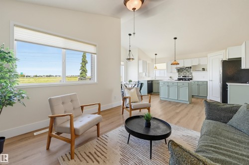Open-concept living space featuring wood-finish flooring, recessed lighting, and a kitchen with an island, pendant lights, and a tiled backsplash - 839 Blacklock Way Sw, Edmonton, AB 