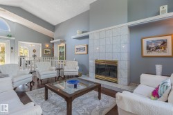 Vaulted ceiling, wood-finish flooring, tiled fireplace with brass trim, arched transom window, and white spindle railing - 