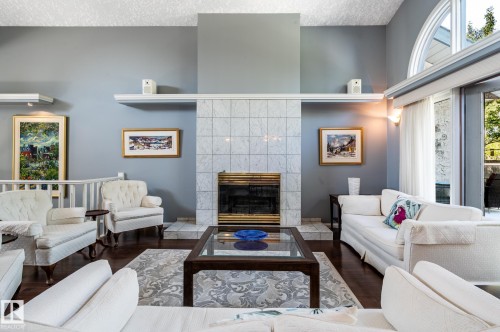 Vaulted ceiling, arched transom window, tiled fireplace surround, dark wood-finish flooring, and a white railing - 8 Edgemont Point(E), St. Albert, AB 