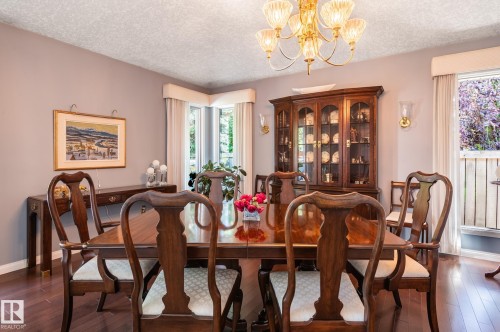 Formal dining area featuring wood-finish flooring, a chandelier, and sconce lighting - 8 Edgemont Point(E), St. Albert, AB 