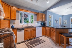 Kitchen featuring wood cabinetry, dark countertops, a bay window, and integrated appliances - 