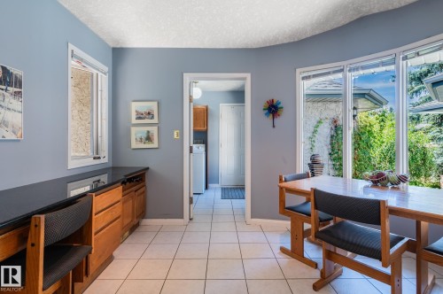 Built-in wood cabinetry with dark countertops, a wall-mounted window, tiled flooring, and a large bay window - 8 Edgemont Point(E), St. Albert, AB 