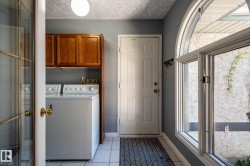 Laundry area with wood cabinetry, tiled flooring, and an arched window - 