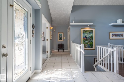 Leaded glass entry door, tile flooring, painted railing, recessed shelving, and a wall-mounted light fixture - 8 Edgemont Point(E), St. Albert, AB 