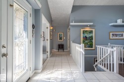 Leaded glass entry door, tile flooring, painted railing, recessed shelving, and a wall-mounted light fixture - 