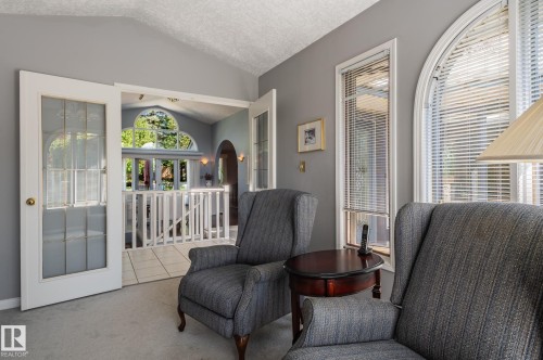 Arch-top window with blinds, French doors with frosted glass, vaulted ceiling, and interior balcony with white railing - 8 Edgemont Point(E), St. Albert, AB 