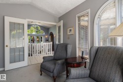 Arch-top window with blinds, French doors with frosted glass, vaulted ceiling, and interior balcony with white railing - 