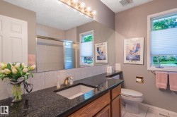 Vanity with a dark countertop and integrated sink, gold-toned faucet, and wood-finish cabinetry - 