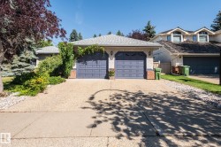 Attached two-car garage with panel doors, brick accents, and exterior lighting - 