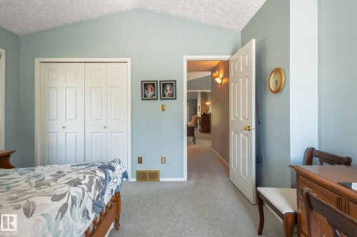 Vaulted ceiling with textured finish, bi-fold closet doors, wall-mounted sconce lighting, and light-toned carpeting - 8 Edgemont Point(E), St. Albert, AB 