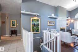Vaulted ceiling, fireplace with tile surround, white spindle railing, arched window, and wood-finish flooring - 