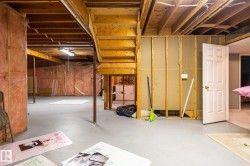 Unfinished lower level with exposed wood joists, insulated walls, and a finished concrete floor - 