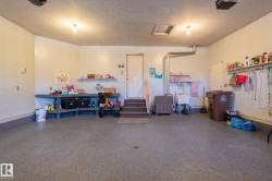 Spacious garage with textured flooring, a utility sink, and built-in shelving - 