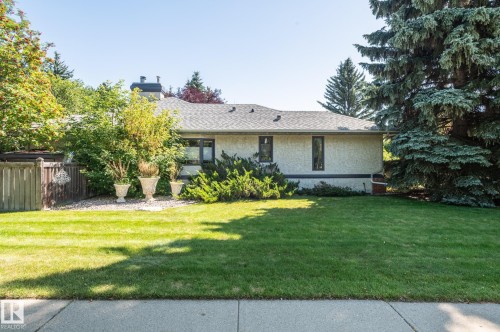 Stucco exterior, gray shingle roof, dark window frames, mature landscaping, and a wooden privacy fence - 8 Edgemont Point(E), St. Albert, AB 