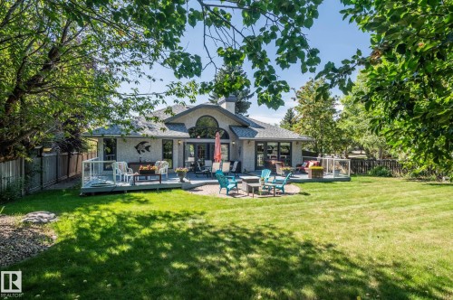 Expansive green lawn with mature trees and a multi-level deck featuring glass railings - 8 Edgemont Point(E), St. Albert, AB 