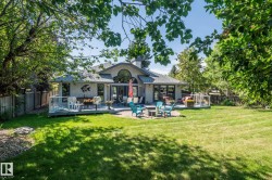 Expansive green lawn with mature trees and a multi-level deck featuring glass railings - 