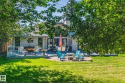 Spacious backyard featuring a manicured lawn, a large multi-level deck, and a circular paver patio - 