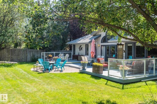 Expansive backyard featuring a manicured lawn, a multi-level deck with glass railings, a brick patio, and mature trees providing natural shade - 8 Edgemont Point(E), St. Albert, AB 