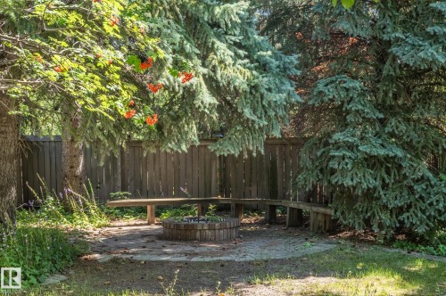 Private outdoor area with a wood privacy fence, integrated wooden bench seating, and a built-in fire pit - 8 Edgemont Point(E), St. Albert, AB 