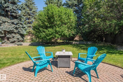 Expansive backyard featuring a circular paver patio, lush lawn, and mature trees - 8 Edgemont Point(E), St. Albert, AB 