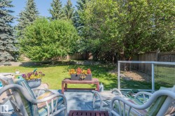 Expansive backyard featuring a manicured lawn, mature trees, and a wooden privacy fence - 