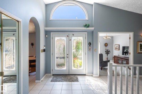 Vaulted entry featuring a decorative arched window, double doors with frosted glass inserts, and white tile flooring - 8 Edgemont Point(E), St. Albert, AB 