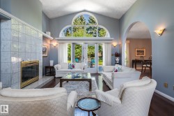 Vaulted ceiling, arched transom windows, French doors, fireplace with tile surround, and an arched entry - 