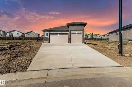 Front exterior featuring a concrete driveway, attached two-car garage, and an additional single-car garage - 32 Dalquist Bay, Leduc, AB 
