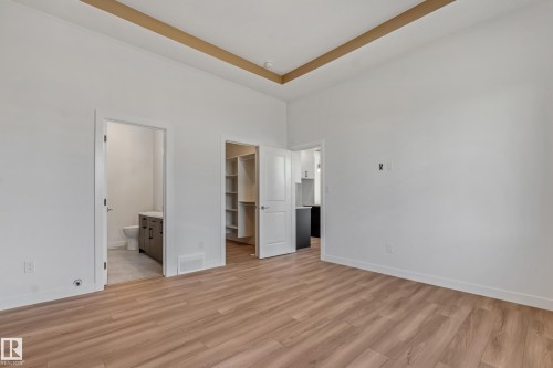 Recessed ceiling with wood-finish accent, wood-finish flooring, white walls, built-in shelving, and a vanity with a white countertop - 32 Dalquist Bay, Leduc, AB 